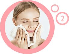 kobieta wycierająca twarz ręcznikiem wewnątrz różowego obramowania z cyfrą 2